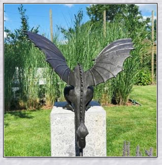 Precision-crafted fire-breathing dragon sculpture serving as a captivating water feature in a lush garden setting