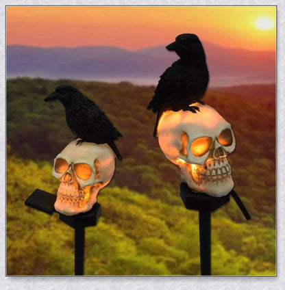 A solar-powered landscape light in the shape of a crow perched on a skull, providing an eerie and captivating outdoor decoration.