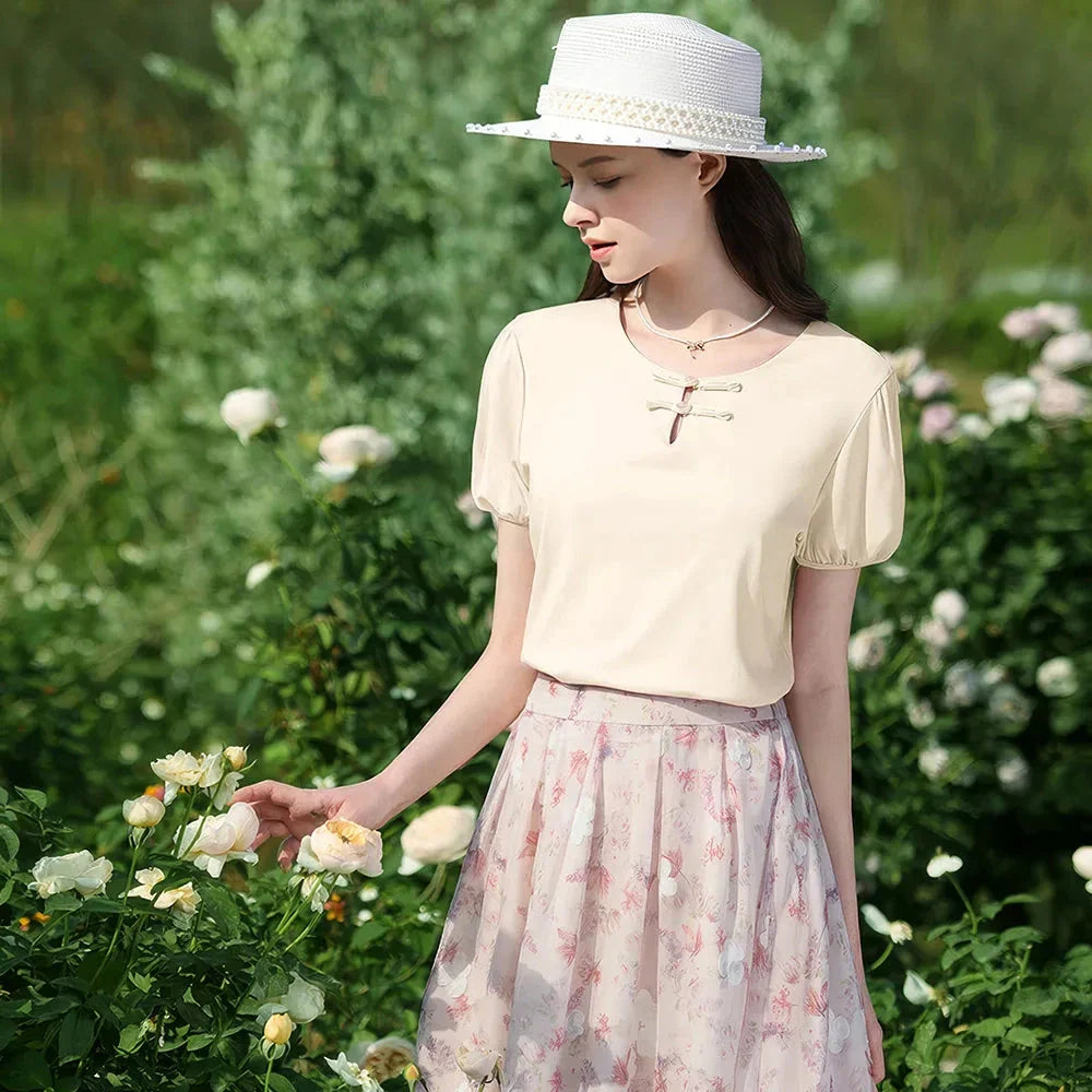 Woman wearing a chic, plated puff short-sleeve summer top in a cream apricot color