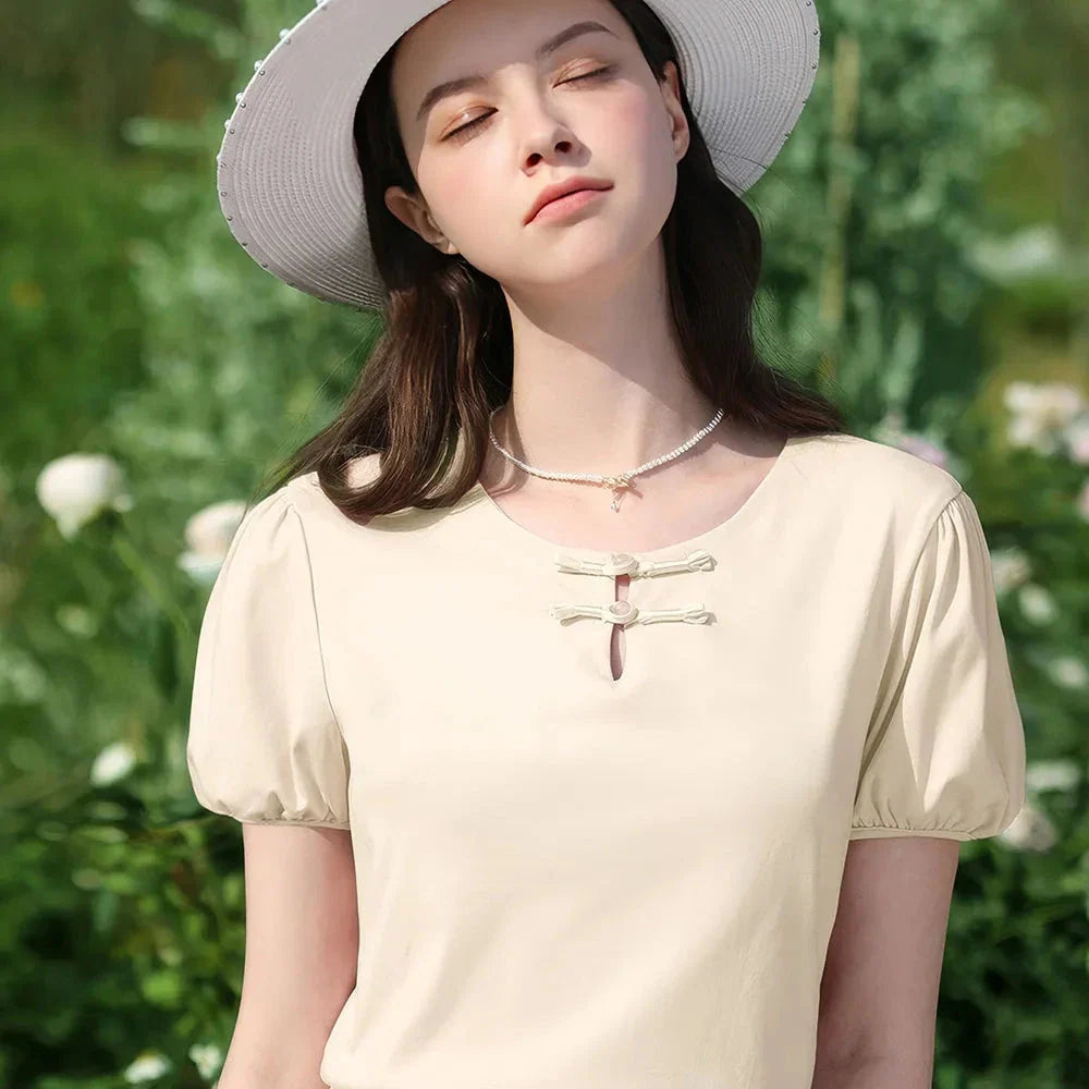 Woman wearing a chic, plated puff short-sleeve summer top in a cream apricot color