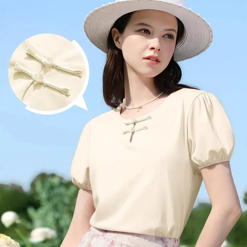 Woman wearing a chic, plated puff short-sleeve summer top in a cream apricot color