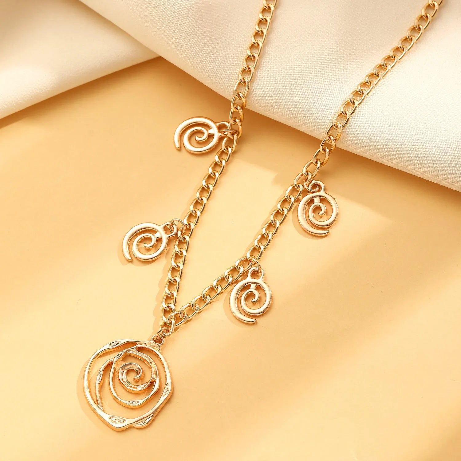 Gold spiral donut alloy jewellery set showing necklace, bracelet, and ear hooks on a plain background.