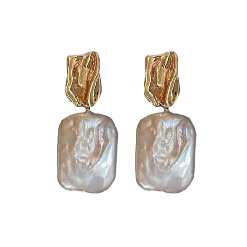 A pair of square stud earrings with a natural freshwater pearl in a geometric alloy setting.
