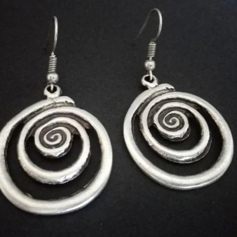 A pair of silver spiral geometric earrings with a distressed texture, shown from the front.
