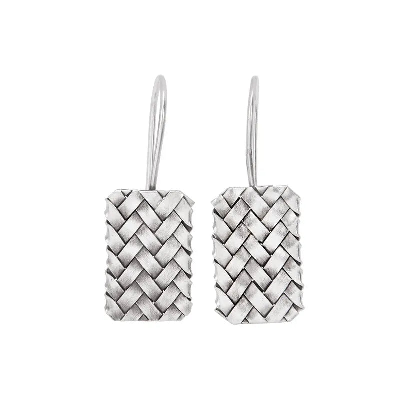 Close-up of a pair of silver geometric stud earrings with a woven diamond plaid pattern on a white background.