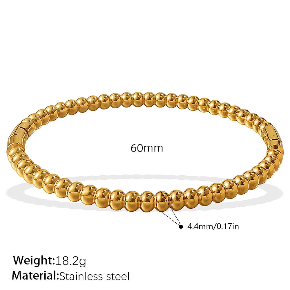 Stainless steel open-end bracelet with a buckle clasp in a gold electroplated finish featuring circle design elements.