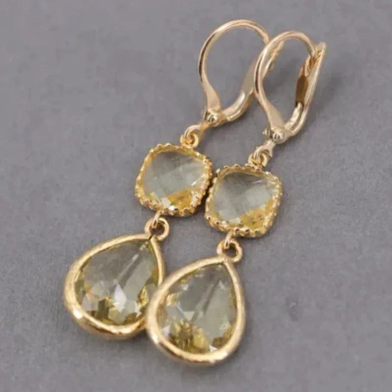 Gold geometric drop earrings with long crystal fringe and water droplet design.