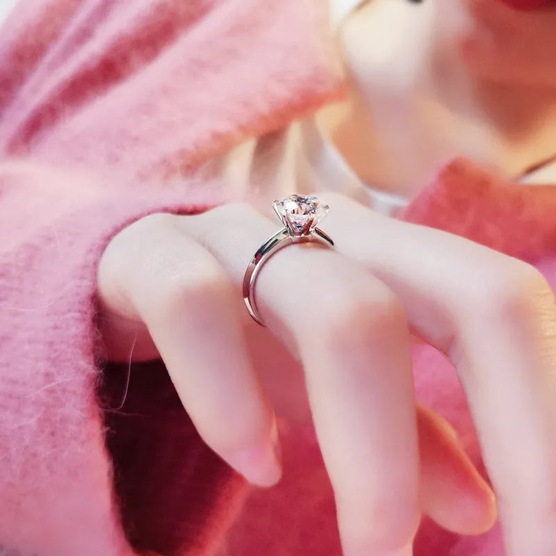 White gold plated geometric ring with a six-claw set zircon stone on a model's finger.