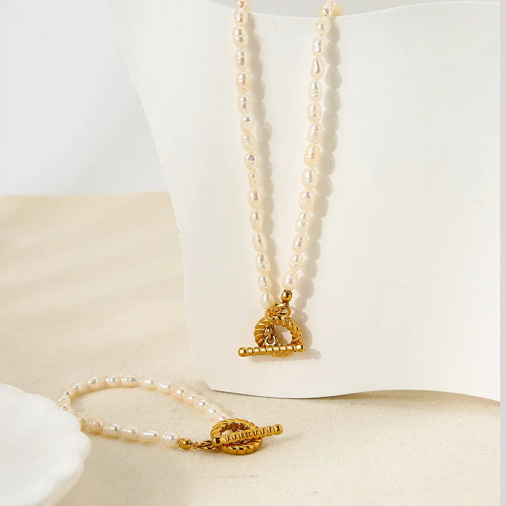Freshwater pearl and geometric stainless steel necklace and bracelet set for women on a white background.