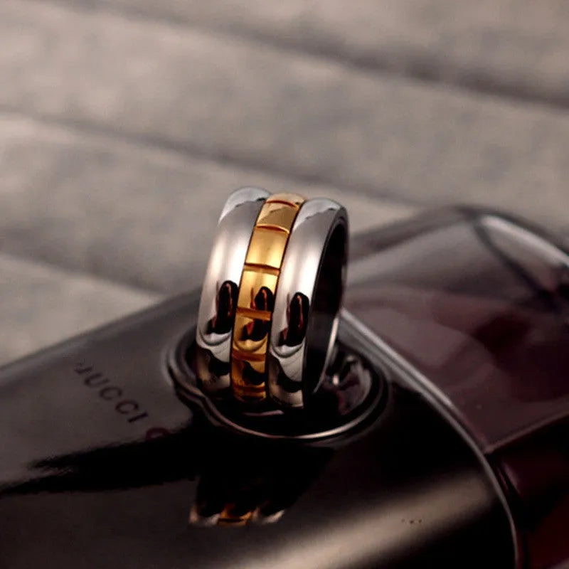 Gold ultra-wide titanium steel men's ring with a rotatable tail component on a finger.
