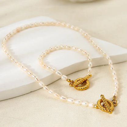 Freshwater pearl and geometric stainless steel necklace and bracelet set for women on a white background.
