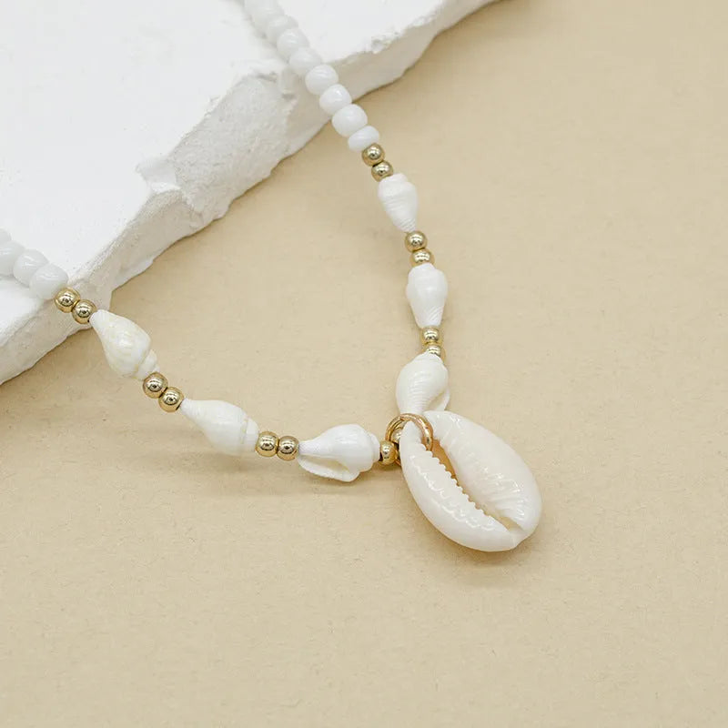 White shell necklace with conch pendant on 45cm chain, electroplated finish.