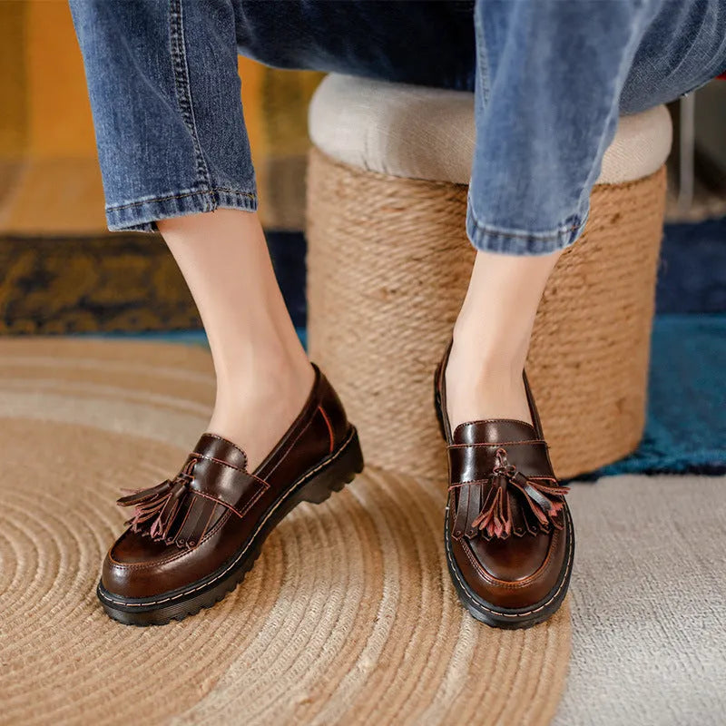 Women's brown leather loafers with tassel detail and a chunky low heel.