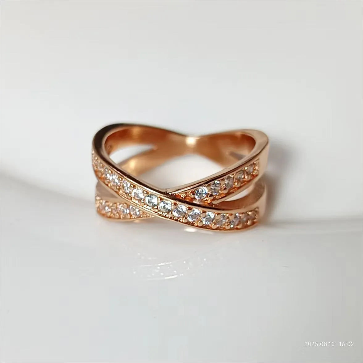 Silver geometric cross ring with micro-inlaid zircon stones on finger, showing simple design with heart-shaped elements