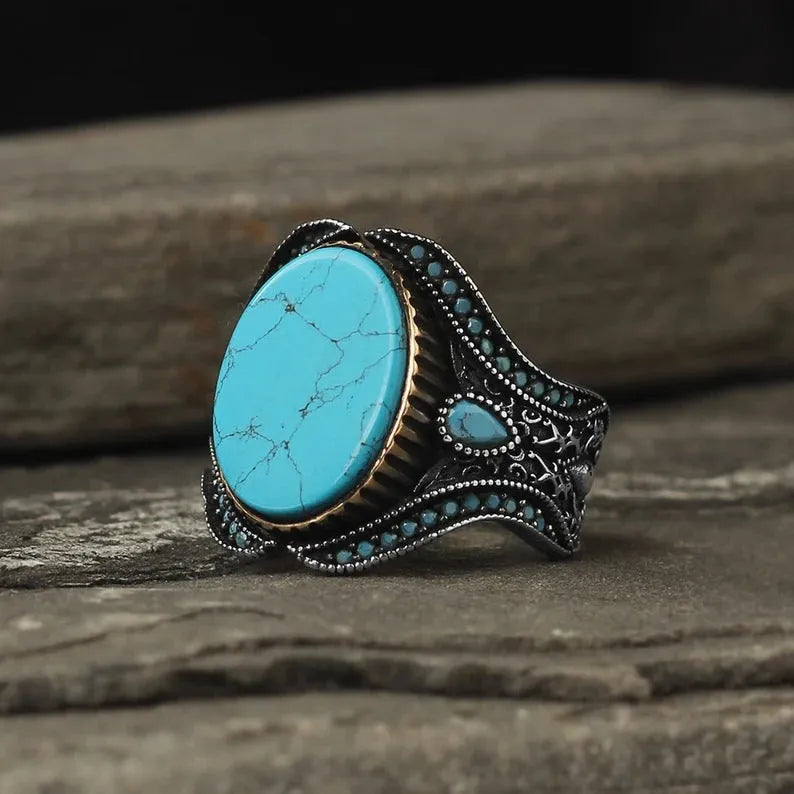 Men's round antique silver alloy ring with a turquoise centre stone on a finger.