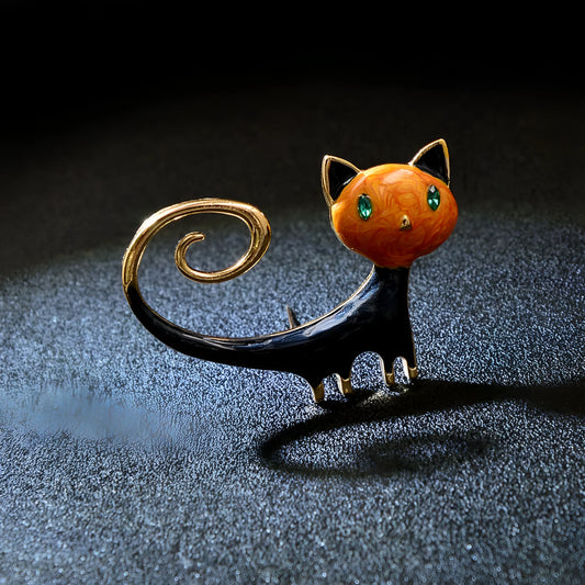 A white or orange alloy fashion brooch featuring a painted cat with its tail up.