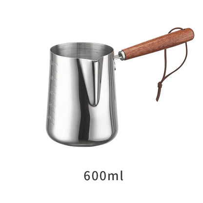 Stainless steel barista milk jug with wooden handle and internal measurement scale for latte art.