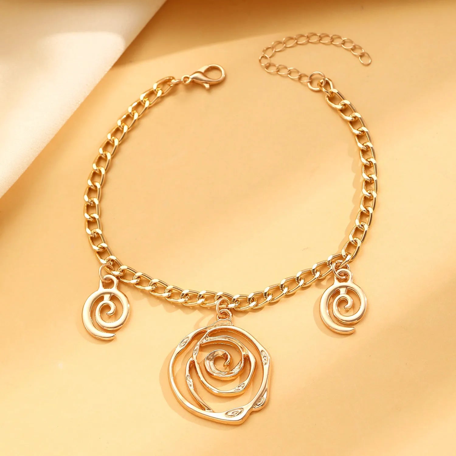 Gold spiral donut alloy jewellery set showing necklace, bracelet, and ear hooks on a plain background.
