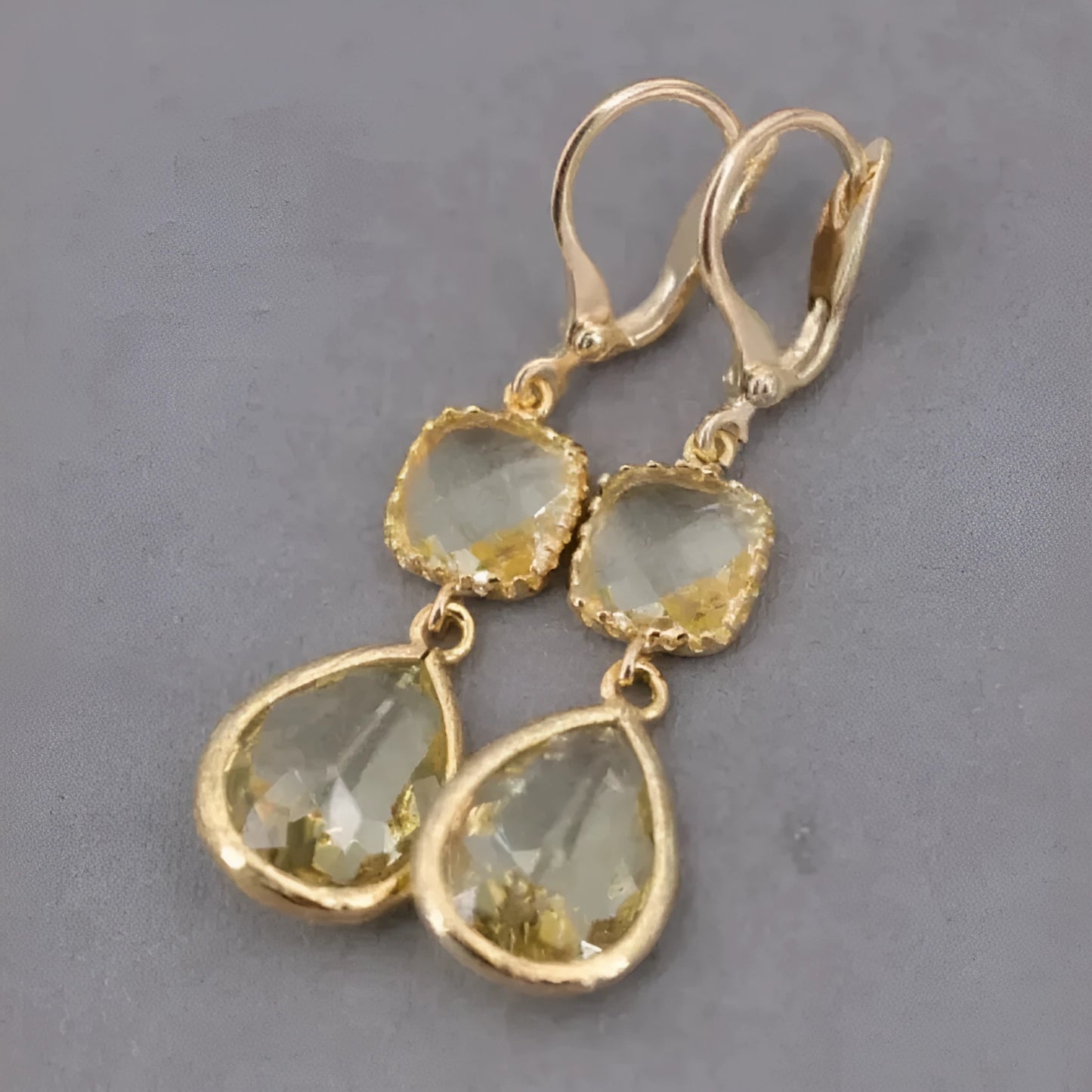 Gold geometric drop earrings with long crystal fringe and water droplet design.