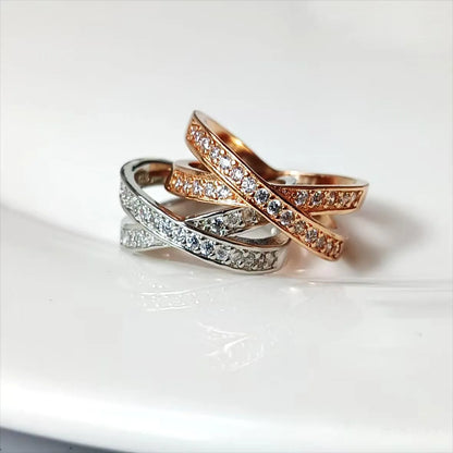 Silver geometric cross ring with micro-inlaid zircon stones on finger, showing simple design with heart-shaped elements