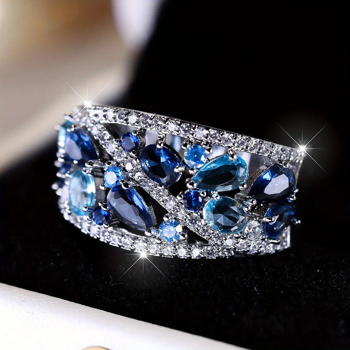 Women's round hollow copper ring showing gold and platinum plating options with sapphire blue and white accents