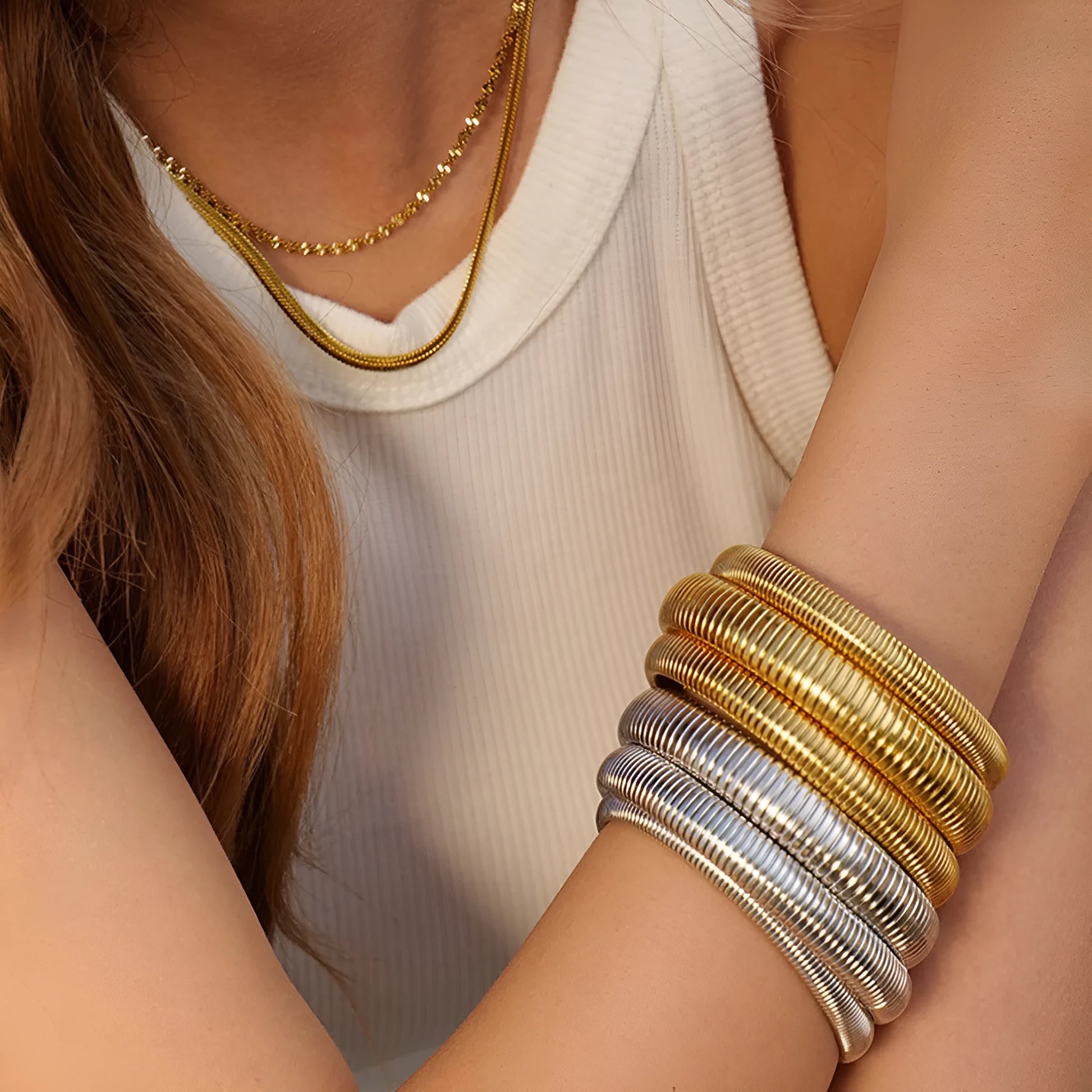 Women's titanium steel elastic bracelet with a vertical stripe pattern in gold, shown on a wrist.