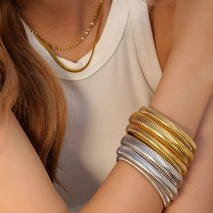 Women's titanium steel elastic bracelet with a vertical stripe pattern in gold, shown on a wrist.