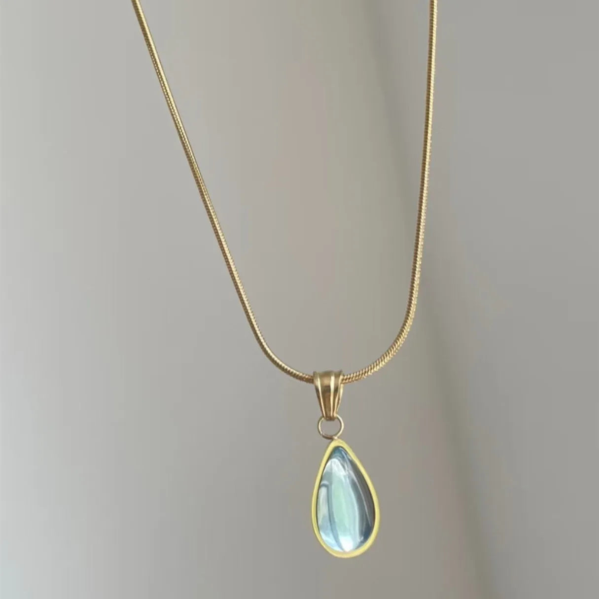 Retro style blue water drop titanium steel pendant necklace with snake bone chain on a white background.