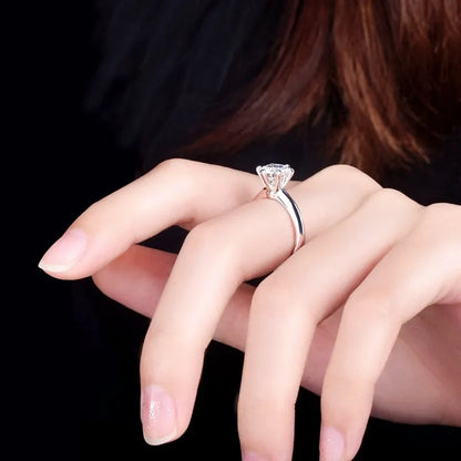White gold plated geometric ring with a six-claw set zircon stone on a model's finger.