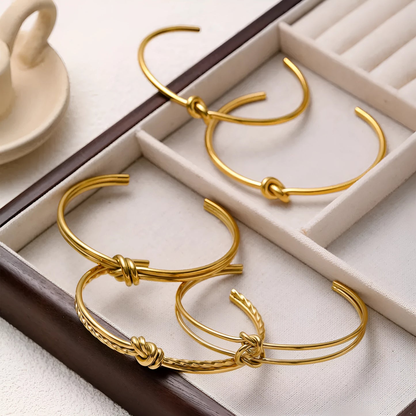 Women's knotted C-shaped open double-layer stainless steel bracelet with gold plating.