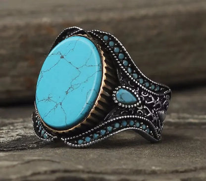 Men's round antique silver alloy ring with a turquoise centre stone on a finger.