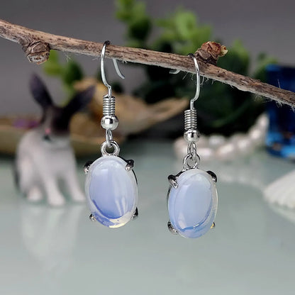 Opal earrings with electroplated alloy construction in moonlight white colour featuring drop shape design with ellipse elements and cross motif