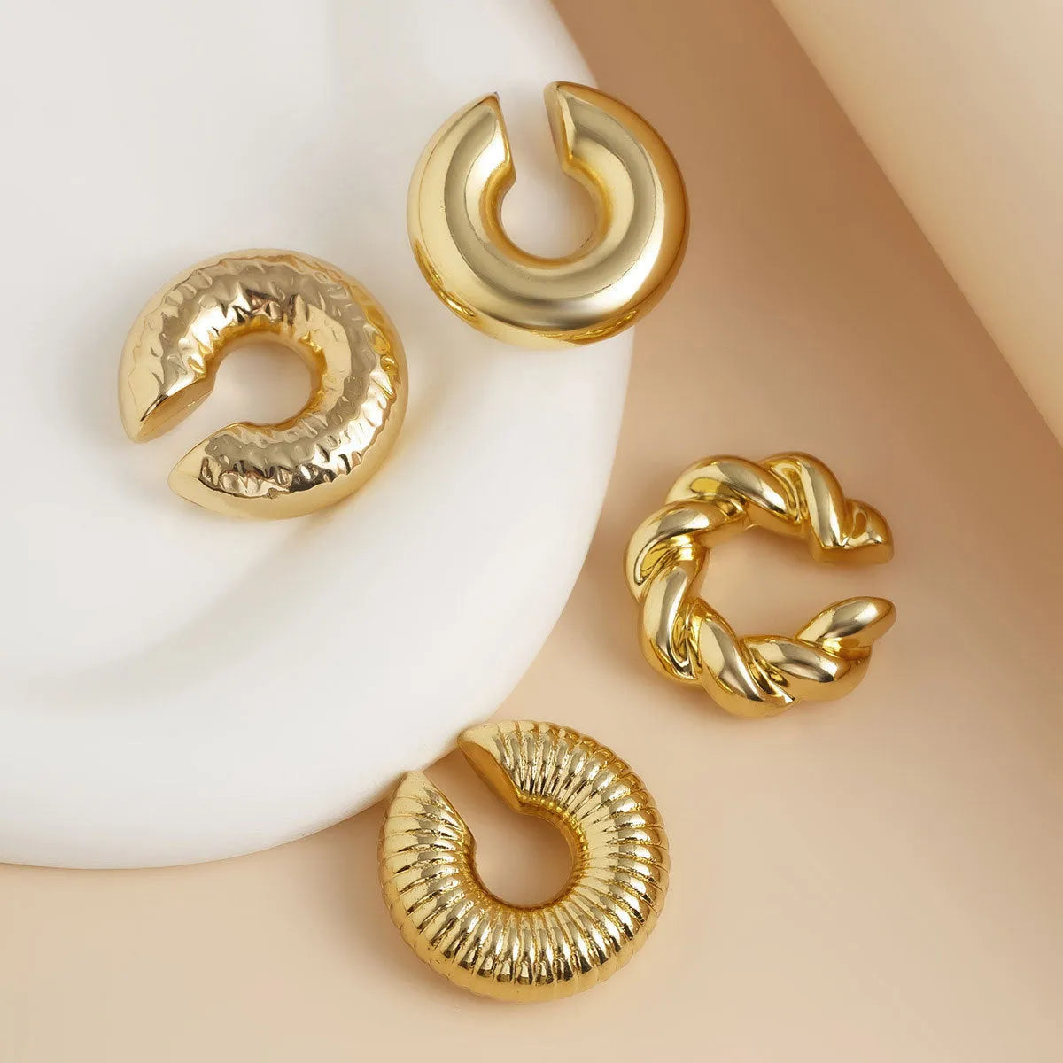 Set of four geometric gold and silver clip-on earrings for non-pierced ears, displayed on a flat surface.