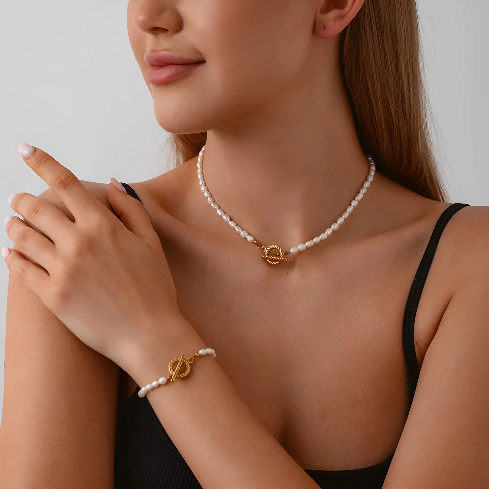 Freshwater pearl and geometric stainless steel necklace and bracelet set for women on a white background.