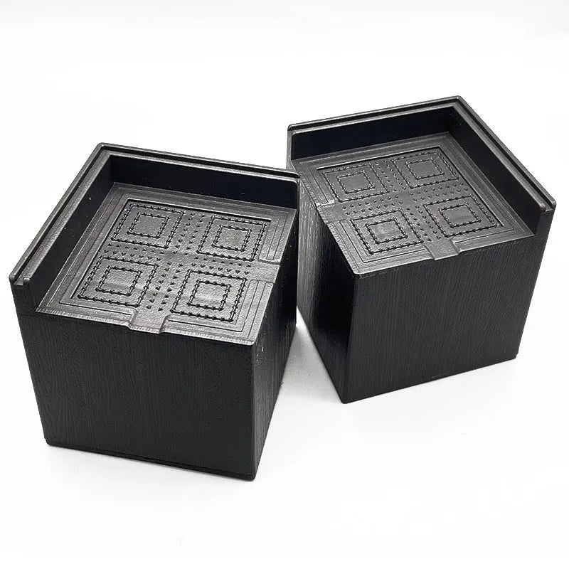Set of four round black plastic furniture risers, each 3cm tall, on a wooden floor.