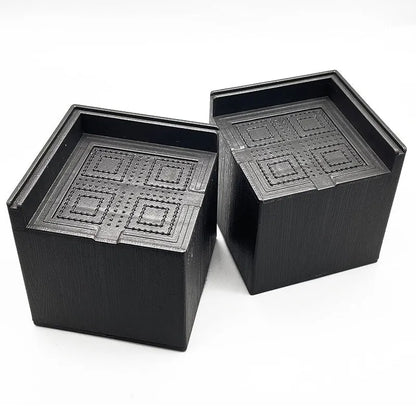 Set of four round black plastic furniture risers, each 3cm tall, on a wooden floor.