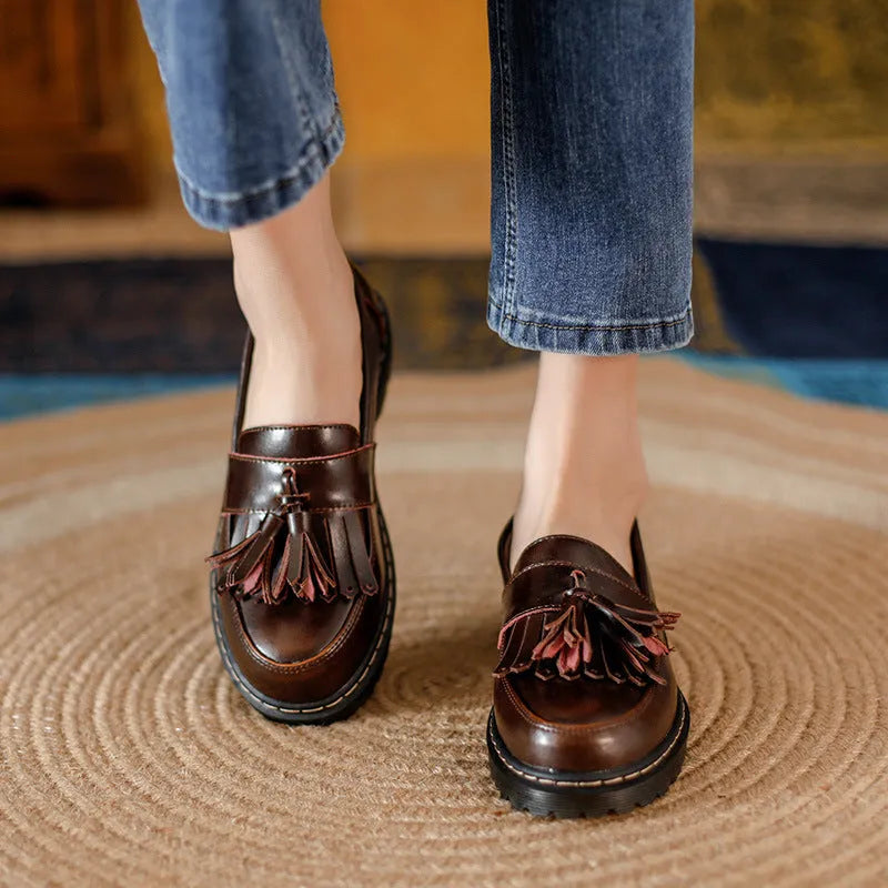 Women's brown leather loafers with tassel detail and a chunky low heel.