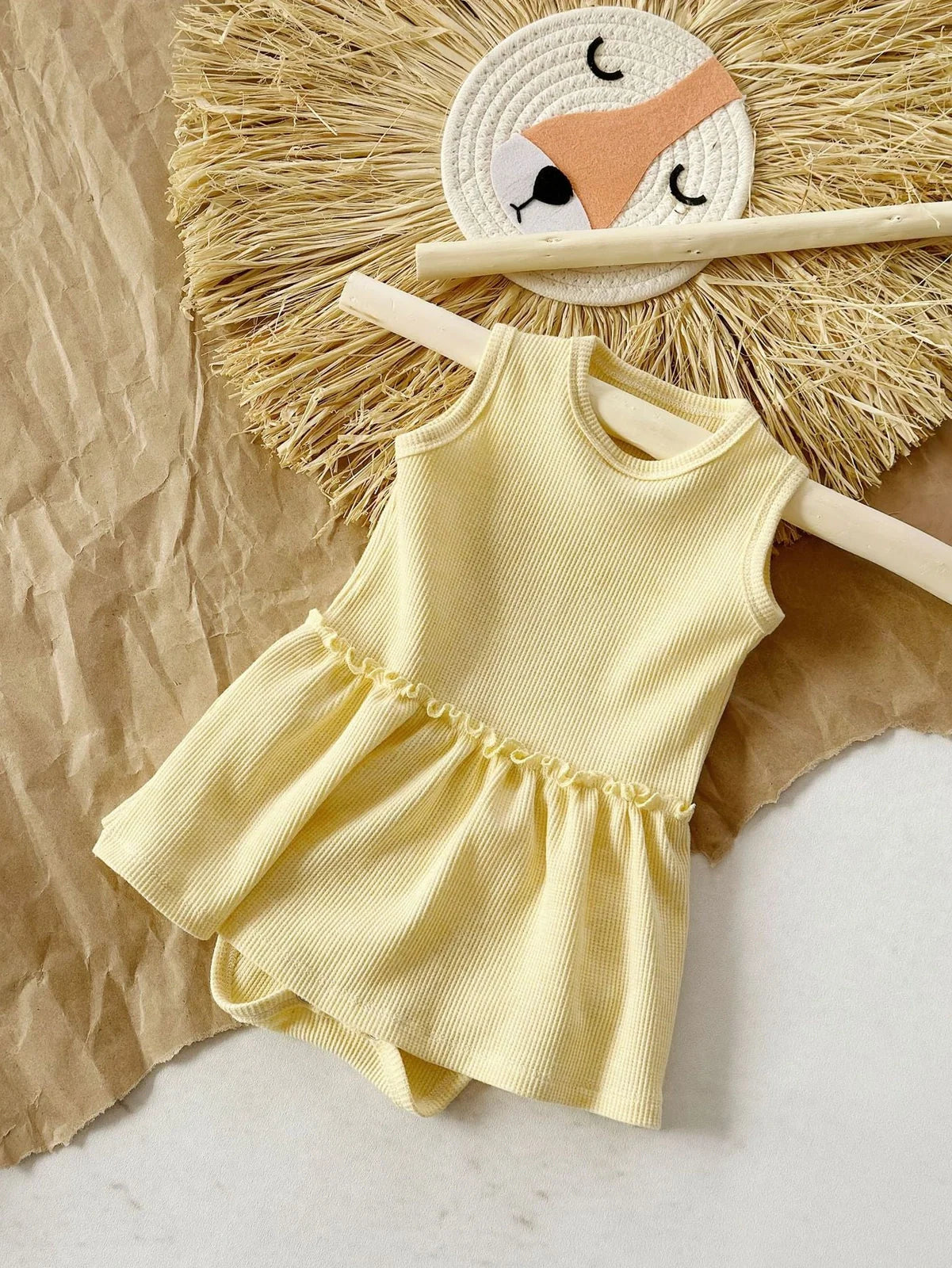 Baby girl wearing pink sleeveless vest onesie with waffle cotton texture and single-breasted closure