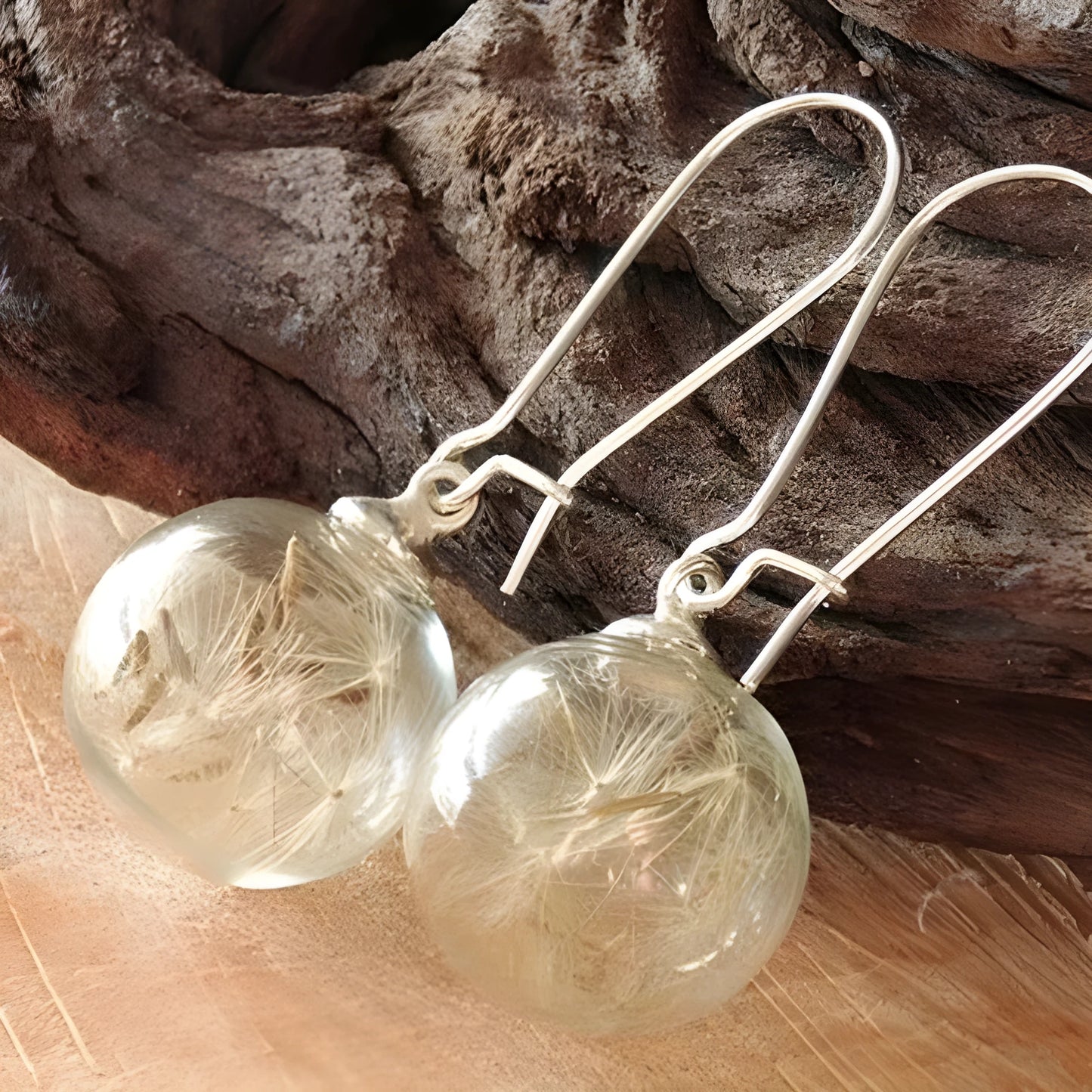 Close-up of a transparent 16mm glass ball earring with a dandelion seed inside, on a silver French hook.