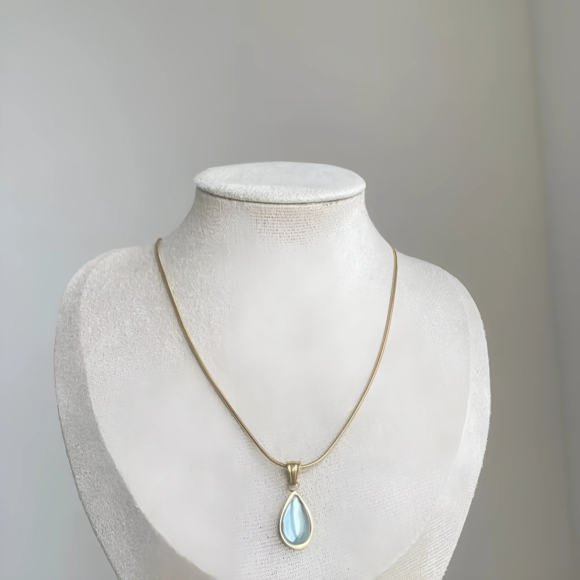 Retro style blue water drop titanium steel pendant necklace with snake bone chain on a white background.