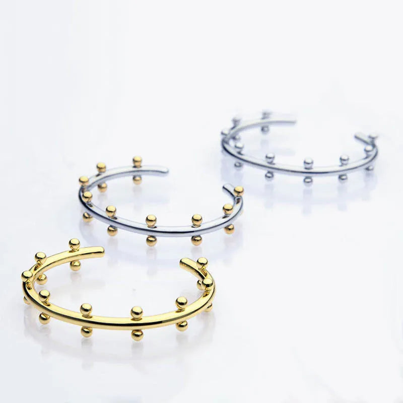 C-shaped stainless steel bracelet with textured rivets and bean beads in gold finish