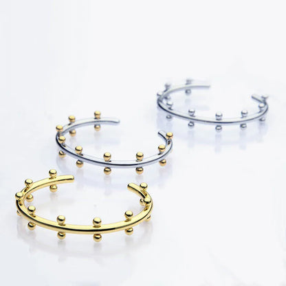 C-shaped stainless steel bracelet with textured rivets and bean beads in gold finish