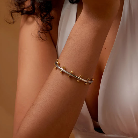 C-shaped stainless steel bracelet with textured rivets and bean beads in gold finish
