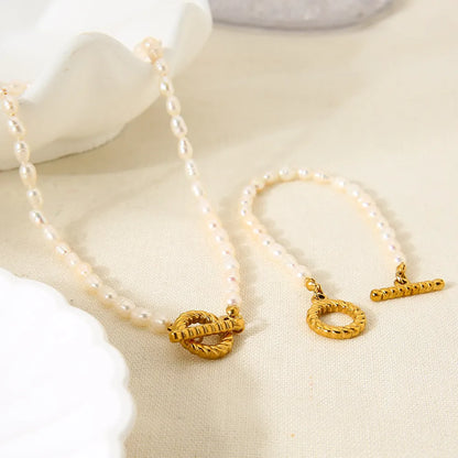 Freshwater pearl and geometric stainless steel necklace and bracelet set for women on a white background.