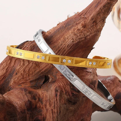 Stainless steel open-end bracelet with a buckle clasp in a gold electroplated finish featuring circle design elements.