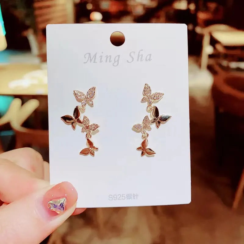 A pair of gold-coloured copper drop earrings with four detailed butterfly charms.