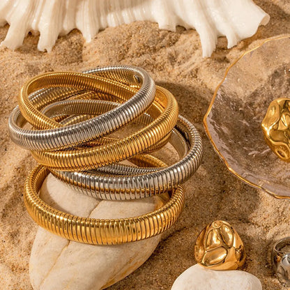 Women's titanium steel elastic bracelet with a vertical stripe pattern in gold, shown on a wrist.