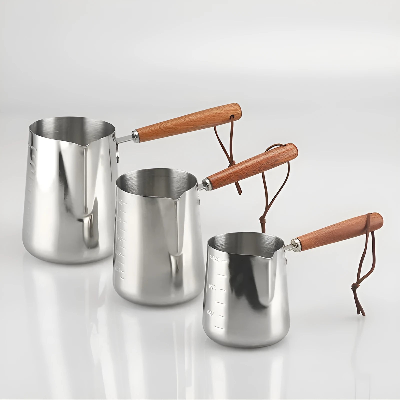 Stainless steel barista milk jug with wooden handle and internal measurement scale for latte art.