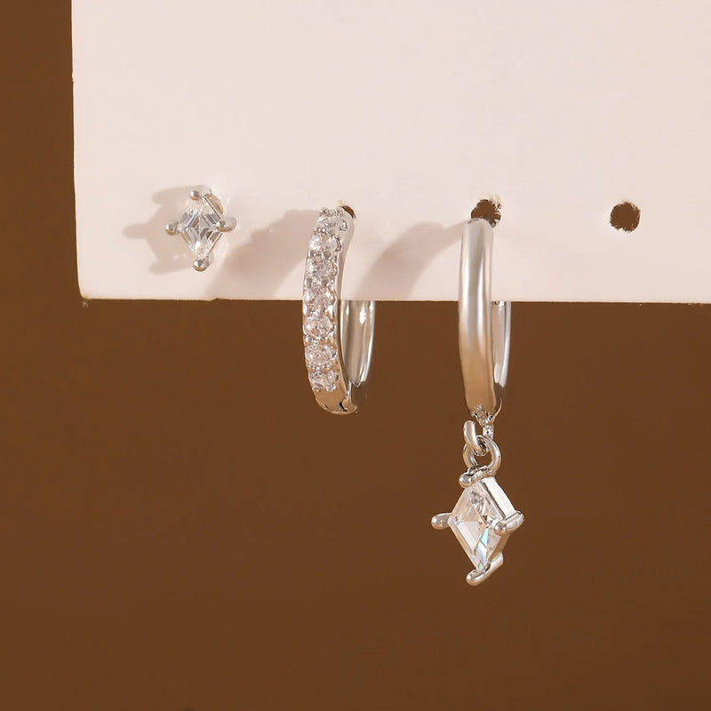 Ladies earring set featuring three-piece inlaid zircon jewellery, comprising clip-on earrings, stud earrings, and dangly drop earrings in geometric shapes with rhombus and quadrilateral elements, available in gold tone or silver white colour options.