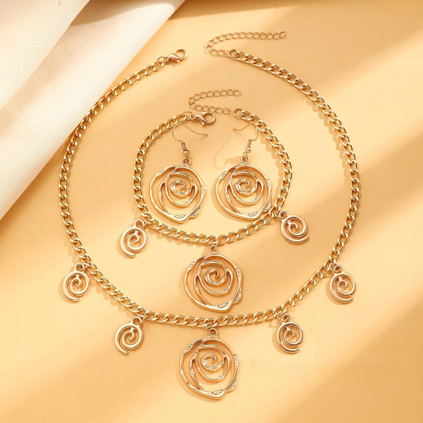 Gold spiral donut alloy jewellery set showing necklace, bracelet, and ear hooks on a plain background.